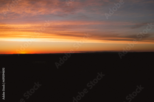 Red sunset on cloudy sky with silhouette