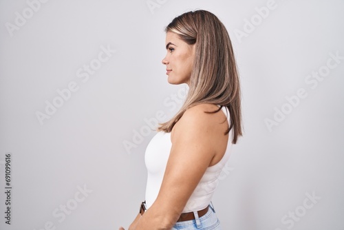 Hispanic young woman standing over white background looking to side, relax profile pose with natural face and confident smile.