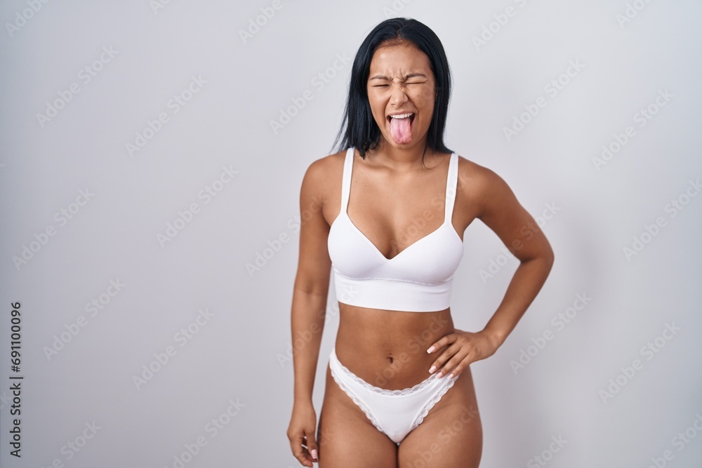 Fototapeta premium Hispanic woman wearing lingerie sticking tongue out happy with funny expression. emotion concept.