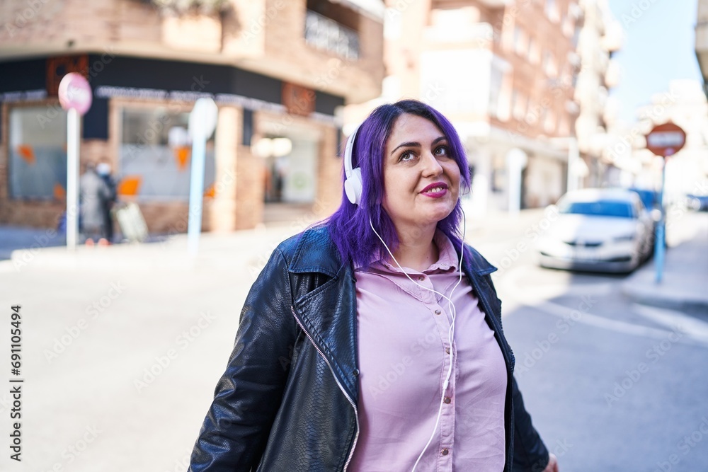 Young beautiful plus size woman smiling confident listening to music at street