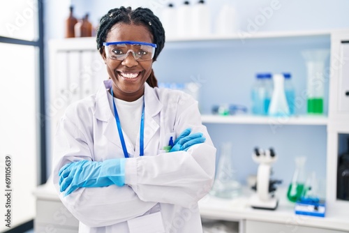 African american woman scientist smiling confident standing with arms crossed gesture at laboratory photo