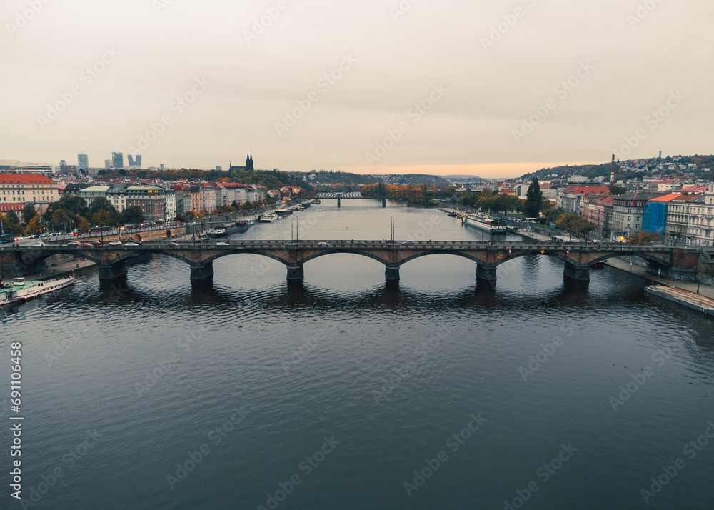Obraz premium PRAGUE, CZECH - October 30, 2023: Aerial view of Prague city (Czech Republic) - famous bridges on Vltava river and old town in autumn time (Fall season). Prague from above on sunset - 