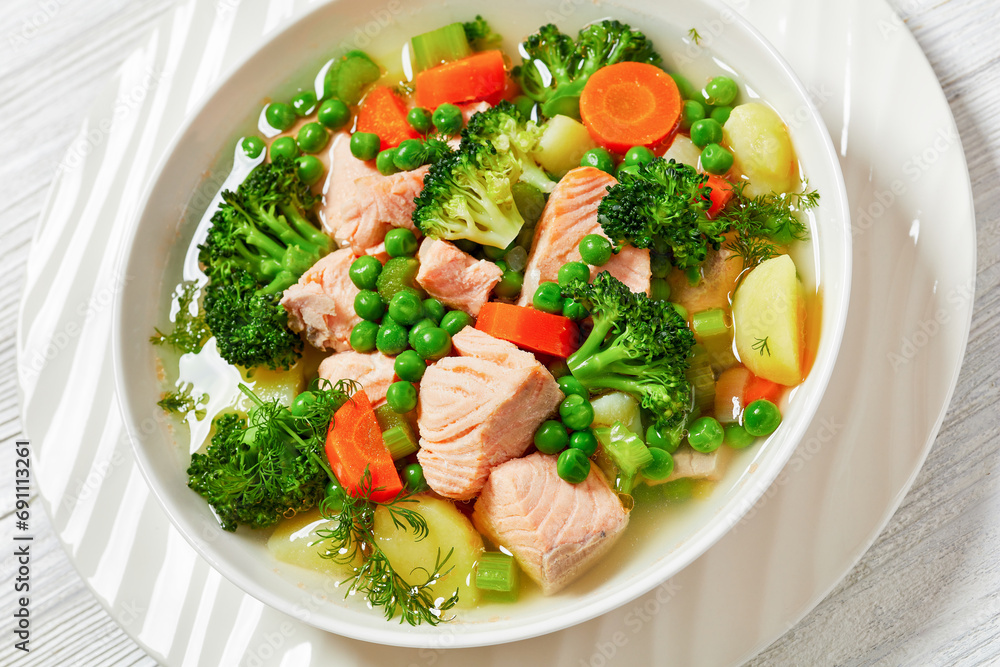salmon, veggies and green herbs soup in bowl salmon, veggies and green herbs soup in bowl