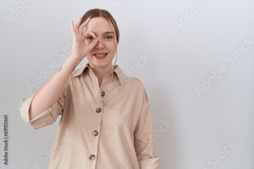 Young caucasian woman wearing casual shirt doing ok gesture with hand smiling  eye looking through fingers with happy face.