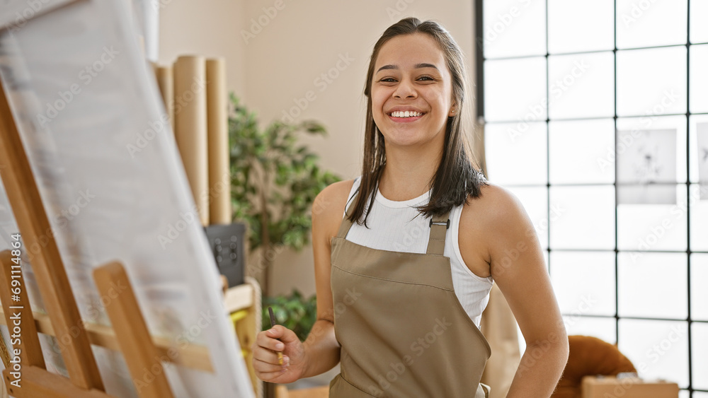 Confident young hispanic artist, smiling beautifully whilst drawing in the studio, exploring her passion