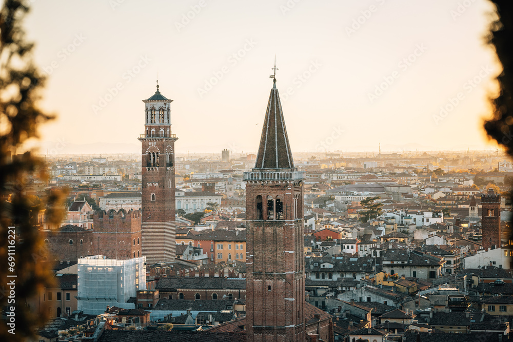 Two striking old church towers looking over the inner city in Italy at sunset as seen from afar