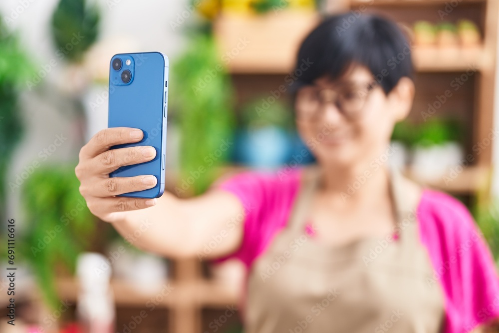 Middle age chinese woman florist make selfie by smartphone at flower shop