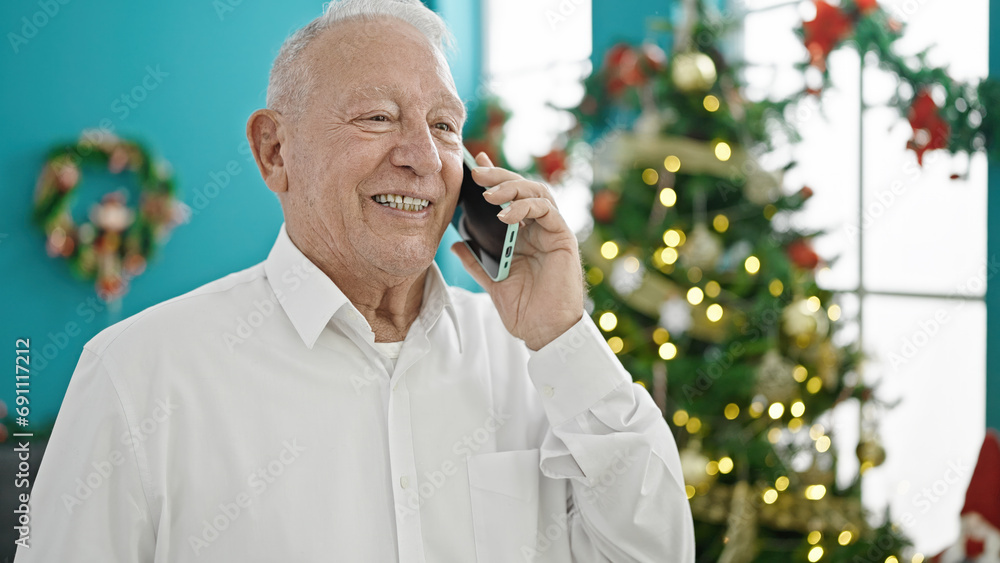 Senior grey-haired man talking on smartphone celebrating christmas at home Senior grey-haired man talking on smartphone celebrating christmas at home