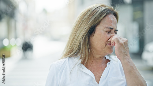 Middle age hispanic woman sneezing at street
