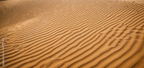  a large sand dune in the middle of the desert with ripples in the sand and trees in the distance.