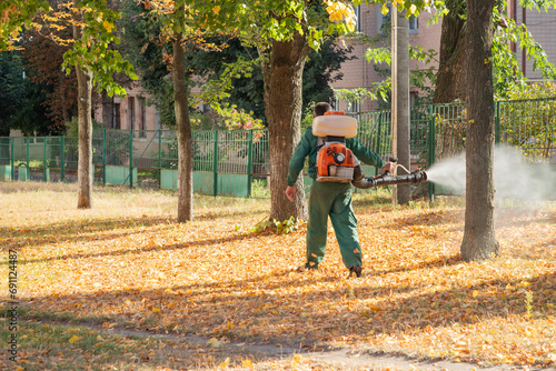 Worker sprays territory with insecticide for mosquitoes or pests or herbicides for weeds.