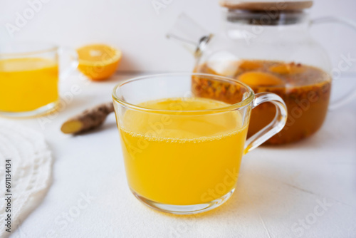 Sea buckthorn tea with orange and ginger in glass cups on a light background. Herbal vitamin tea
