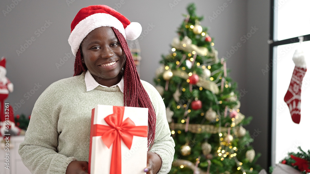African woman with braided hair holding christmas gift at home African woman with braided hair holding christmas gift at home