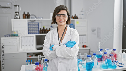 At the research clinic  a confident young scientist stands  arms crossed  in her lab. this hispanic woman  beautiful with a radiant smile  embodies the future of medicine