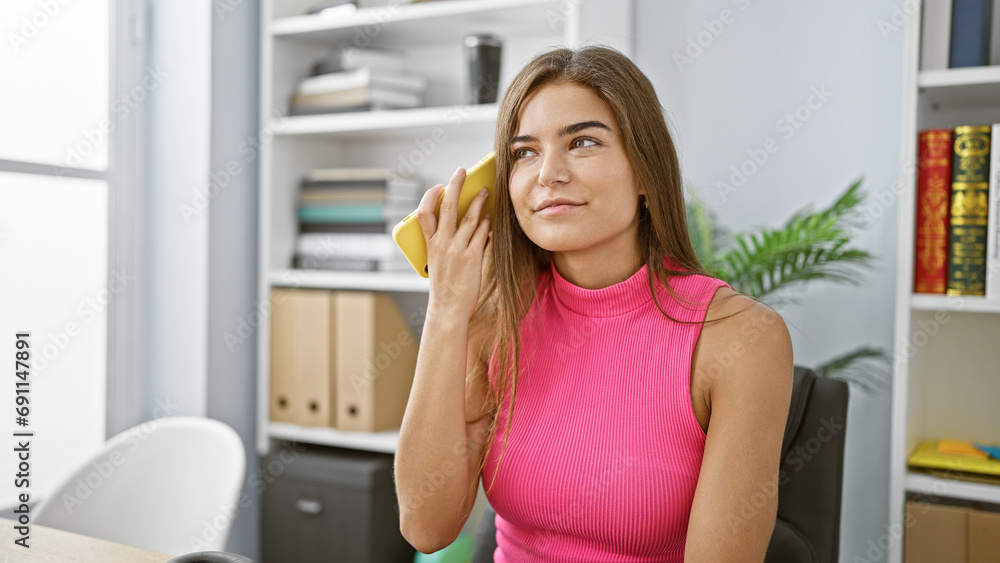 Capture the moment, young, beautiful hispanic female professional, engrossed in work, intently listening to voice message on smartphone at office
