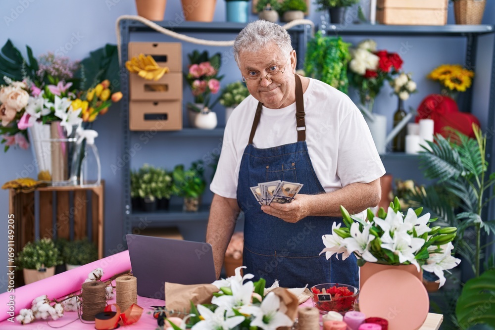 Middle age grey-haired man florist smiling confident counting dollars at florist