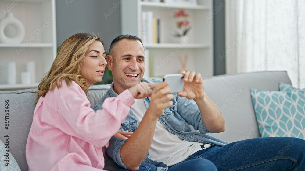 Man and woman couple using smartphone sitting on sofa at home Man and woman couple using smartphone sitting on sofa at home