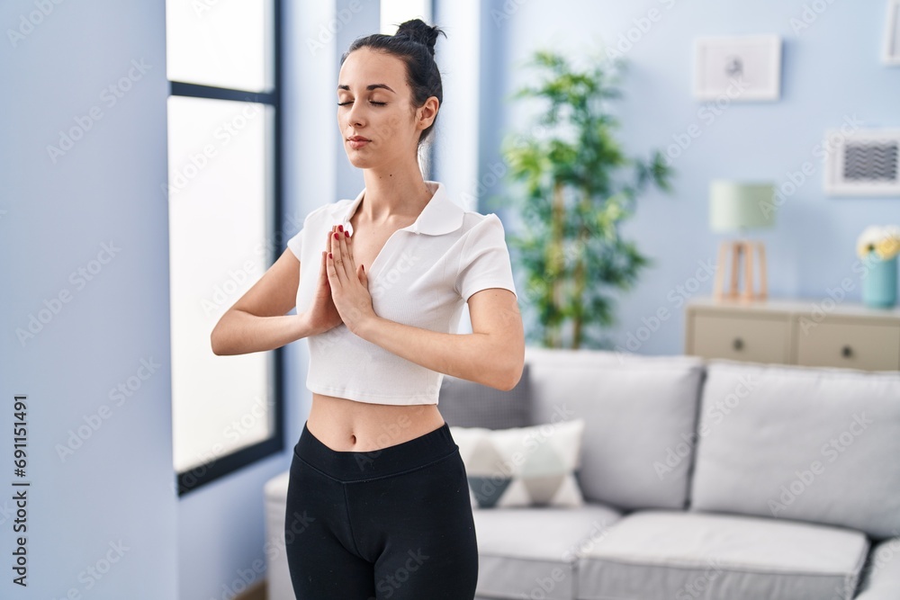 Young caucasian woman training yoga at home