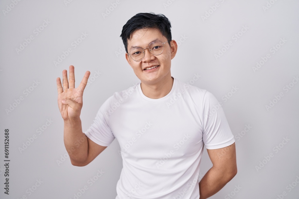 Young asian man standing over white background showing and pointing up with fingers number four while smiling confident and happy. Young asian man standing over white background showing and pointing up with fingers number four while smiling confident and happy.