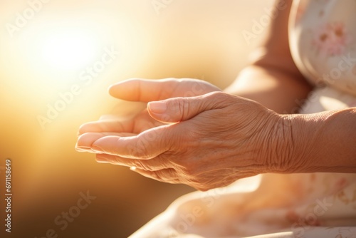 A woman standing outdoors with her hands raised in front of the sun. This image can be used to depict spirituality, hope, and connection with nature