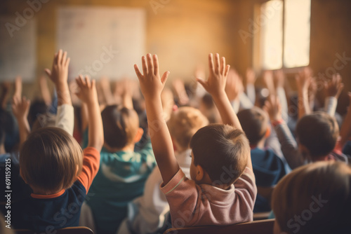 group of children in classroom and raised their hands to answer, blurred background, back view