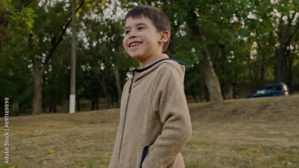 Smiling little boy standing on the meadow wearing a jacket looking at camera. Adorable expression Smiling little boy standing on the meadow wearing a jacket looking at camera. Adorable expression