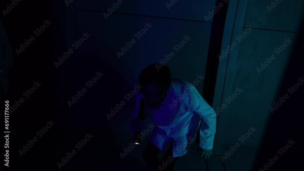 Vulnerable male scientist with a flashlight looking for something in dark corridor. Scared and worried male in white uniform holding a flashlight indoors. High quality 4k footage Vulnerable male scientist with a flashlight looking for something in dark corridor. Scared and worried male in white uniform holding a flashlight indoors. High quality 4k footage
