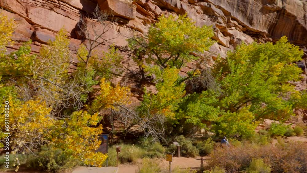 Establishing shot of mountain trail with red rocks background in Hickman Natural Bridge Trail, Capital Reef National Park, Utah, North America. Day time on October 2023. Still camera view. ProRes 422 Establishing shot of mountain trail with red rocks background in Hickman Natural Bridge Trail, Capital Reef National Park, Utah, North America. Day time on October 2023. Still camera view. ProRes 422