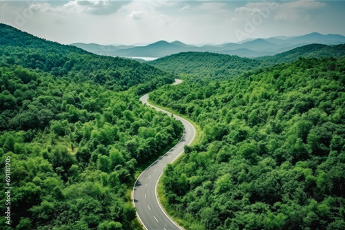 Aerial top view mountain road in dark green forest