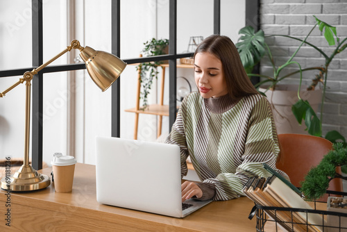 Young woman using laptop at...