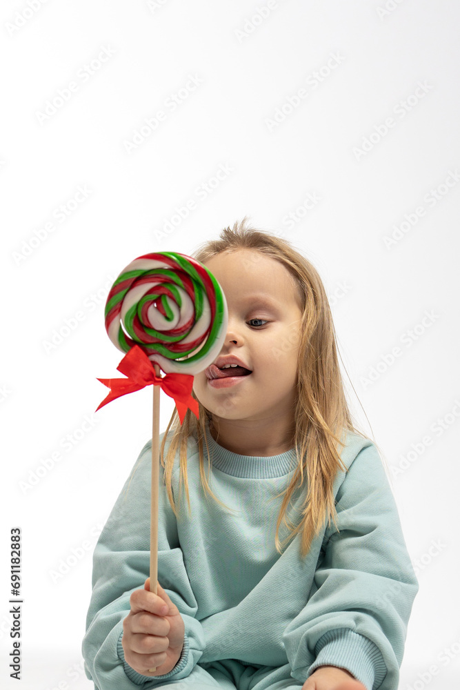 Portrait of funny little blonde girl with sweets lollipop in her hand.
