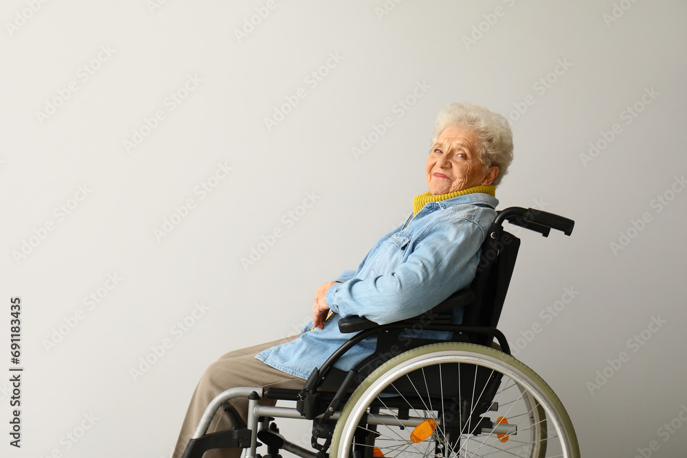 Senior woman in wheelchair on light background Senior woman in wheelchair on light background
