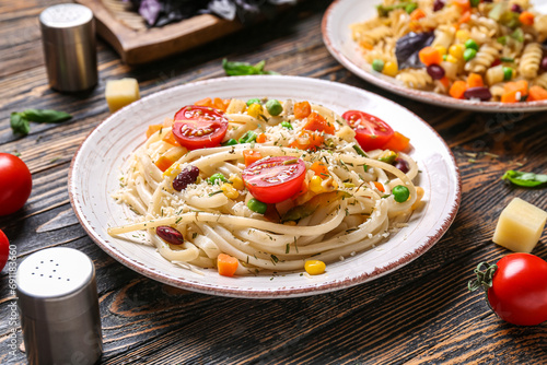 Plate with tasty pasta primavera on wooden background