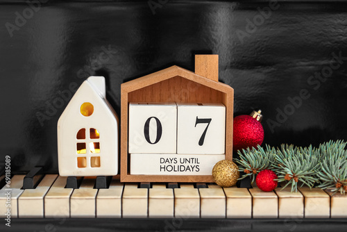 Calendar with text 7 DAYS UNTIL HOLIDAYS and Christmas decor on piano keys photo