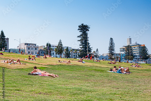 Sunbathers on the grass near Bondi Beach, a beautiful beach; with surfers, public and rock, with clear waters. Sydney, Australia, Dec 2019 photo