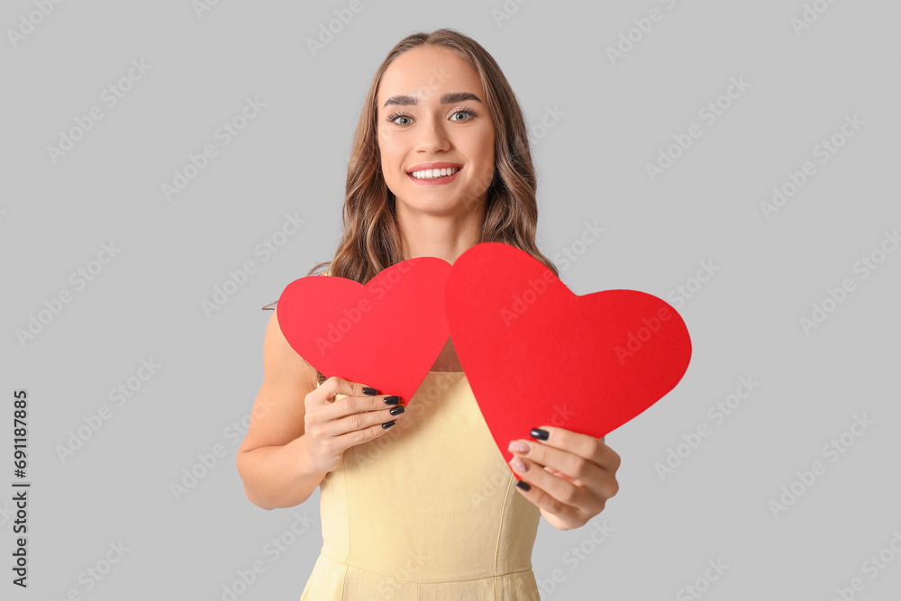 Beautiful young woman with red paper hearts on grey background Beautiful young woman with red paper hearts on grey background