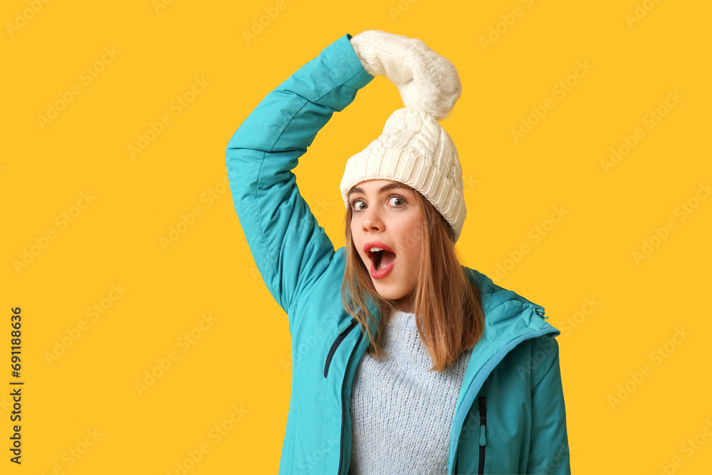 Beautiful young shocked woman in warm winter clothes on yellow background Beautiful young shocked woman in warm winter clothes on yellow background