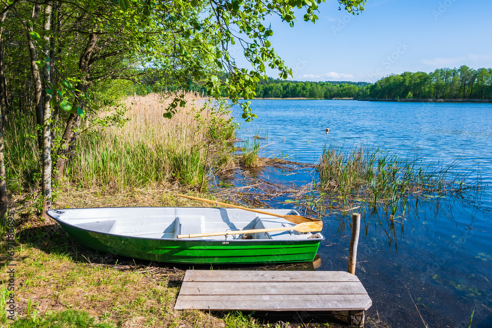 Fishing boat at wooden pier by small lake in Suwalski Landscape Park, Podlasie, Poland Fishing boat at wooden pier by small lake in Suwalski Landscape Park, Podlasie, Poland