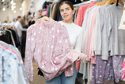 Young positive woman shopping for warm casual clothing in retail shopping store