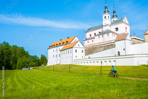 Cyclist riding bike along church in Camaldolese monastery complex on the Wigry lake peninsula, Podlasie, Poland photo