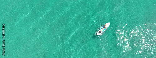 Aerial drone ultra wide panoramic photo of young unidentified woman practising paddle board or SUP in tropical Caribbean sapphire crystal clear calm waters photo