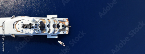 Aerial drone ultra wide panoramic photo with copy space of latest technology modern mega yacht with wooden deck and helipad anchored in deep blue Aegean sea