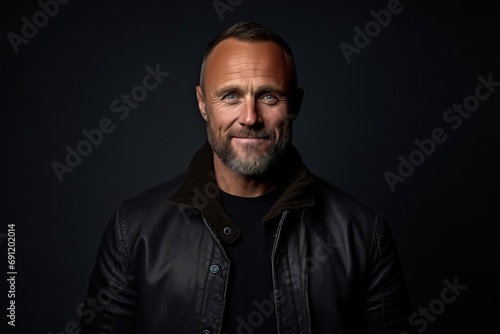 Handsome mature man in a black leather jacket on a dark background.
