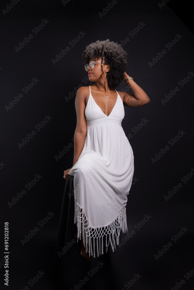 Fototapeta premium Beautiful woman, with black power hair, wearing glasses, standing wearing white clothes posing for a photo.