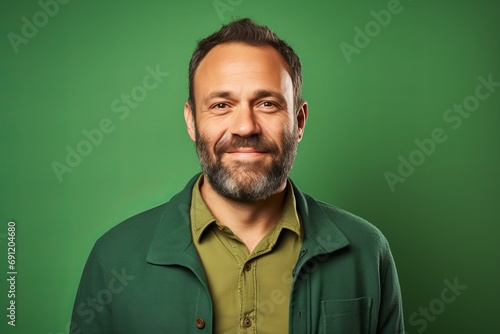 Portrait of a man with a beard on a green background.