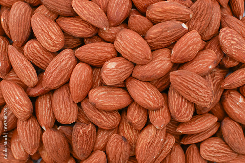 A pile of raw almonds, The almonds are brown and have a rough texture. They are a healthy snack or addition to a meal.