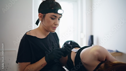 Focused tattooist holding machine at home closeup. Woman changing consumable photo