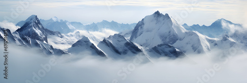 a panoramic view of snowy mountains with snow covered peaks covered with fog and snow in winters photo
