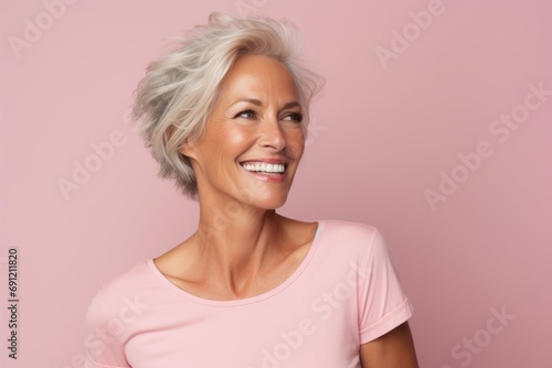 Portrait of a happy senior woman with short white hair over pink background