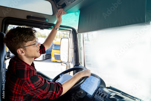 Young truck driver activating tachometer , sitting in truck cabin , ready to go  photo